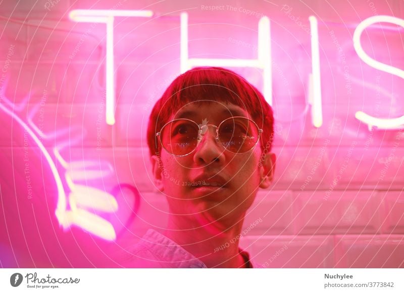 Junger asiatischer Hipster tausendjähriger Mann im Streetstyle-Modekonzept und mit Sonnenbrille in rosa Neonlicht Stilrichtung neonfarbig Jahrtausende gen z