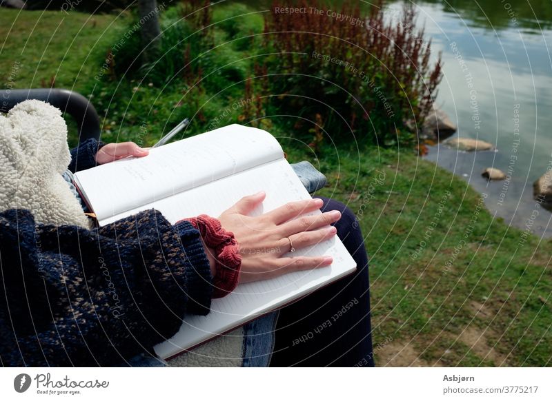 Frau sitzt mit Notebook im Park lernen studierend Notizblock Kugelschreiber Text schreiben Papier Menschen kreativ Bleistift Schreibstift zeichnen Buch Hinweis