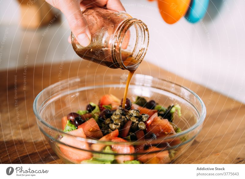 Nahaufnahme von Frauenhänden, die Dressing über einen Salat gießen. Salatbeilage Gemüse Essig balsamisch eingießen frisch Gewürz Gesundheit natürlich