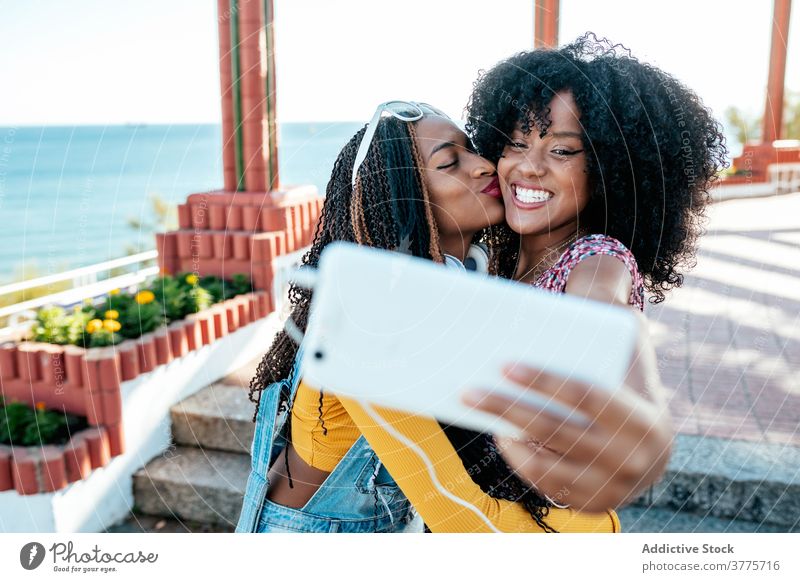 Fröhliche schwarze Freunde nehmen Selfie in der Stadt Umarmung Smartphone Frauen Freundschaft heiter Bonden benutzend Sommer Spazierweg ethnisch Afroamerikaner