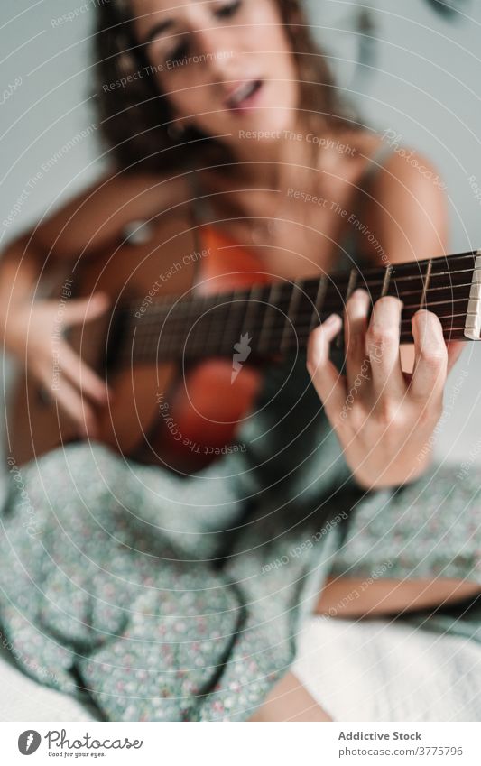 Positive Frau spielt Gitarre im Schlafzimmer Gitarrenspieler Musik spielen heiter Lachen Talent unterhalten sorgenfrei Instrument ethnisch akustisch gemütlich