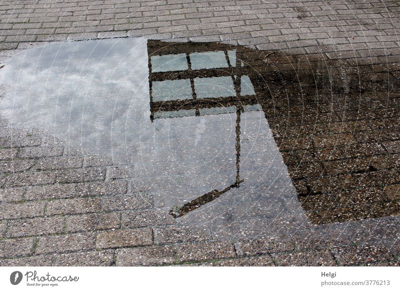 Laterne, Glasdach und Wand vor wolkigem Himmel spiegeln sich in einer Pfütze Spiegelung Pflastersteine Wasser nass Wolken Reflexion & Spiegelung Außenaufnahme