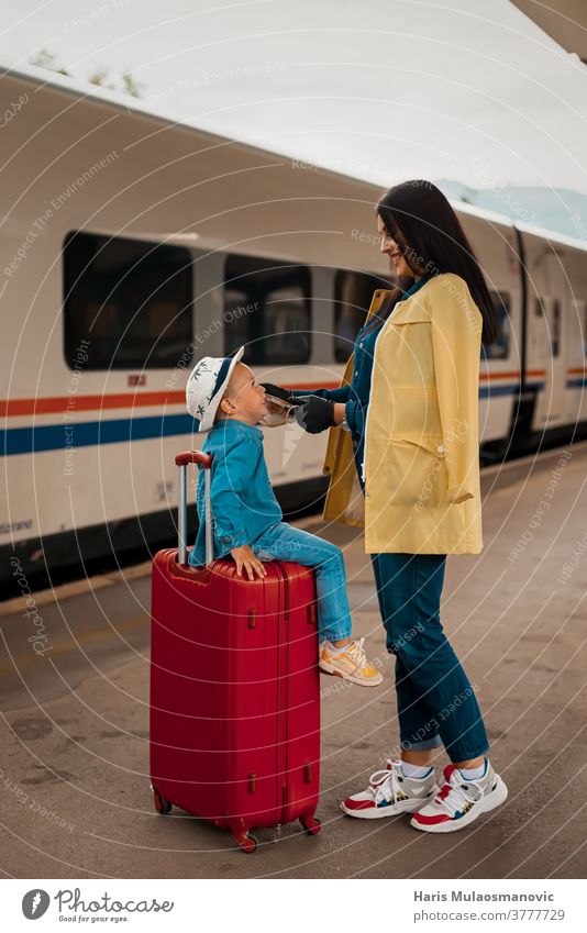 Mutter und Kind mit Gesichtsmaske und Gepäcktaschen, reisefertig Erwachsener Tasche Taschen schön Kaukasier Großstadt Corona-Virus Covid-Reisen covid-19