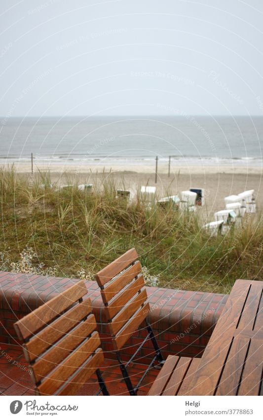 Regentag - leere nasse Stühle stehen am Tisch auf der Strandpromenade mit Blick auf den Strand mit Strandkörben und die rauhe Nordsee Düne Sand Wasser Meer