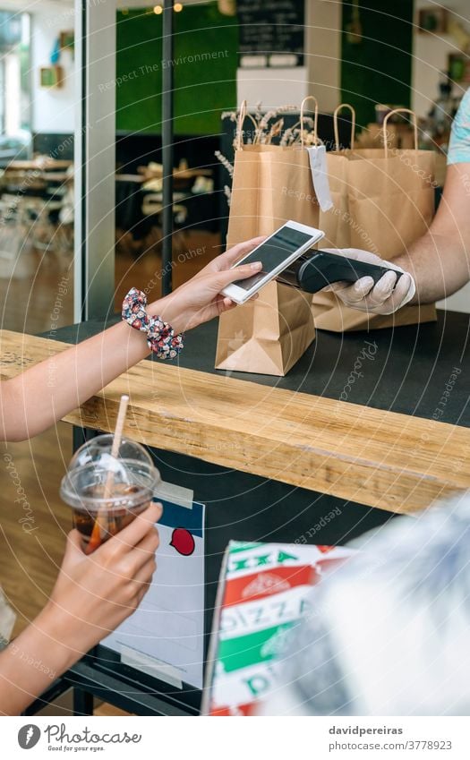 Nicht erkennbare Frau, die mit dem Handy einen Mitnahmeauftrag bezahlt unkenntlich bezahlen Mobile wegnehmen nfc Pos-Terminal Lebensmittel-Lieferung trinken