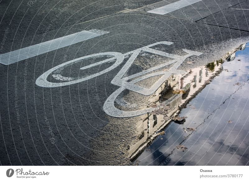 Radweg an Pfütze Fahrrad Piktogramm Straße Asphalt zeichen markierung Fahrradweg Regen Nass Reflexion & Spiegelung Haus Himmel Stadt Energiewende Verkehrswende