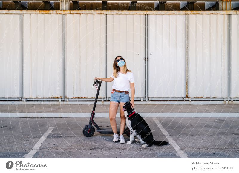 Junge Frau mit Elektroroller und Hund Mundschutz aktiv Reiter Haustier Freund Zusammensein Begleiter Teenager jung Lifestyle Verkehr Fahrzeug Freundschaft