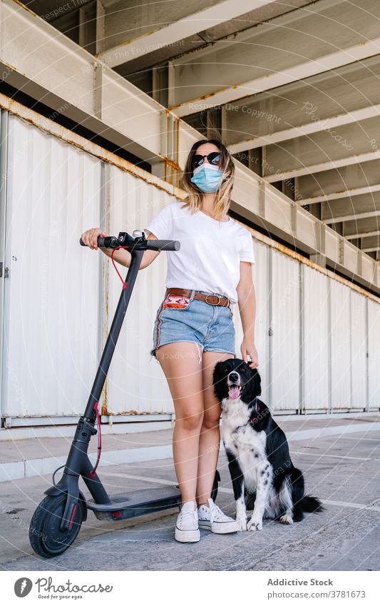 Junge Frau mit Elektroroller und Hund Mundschutz aktiv Reiter Haustier Freund Zusammensein Begleiter Teenager jung Lifestyle Verkehr Fahrzeug Freundschaft