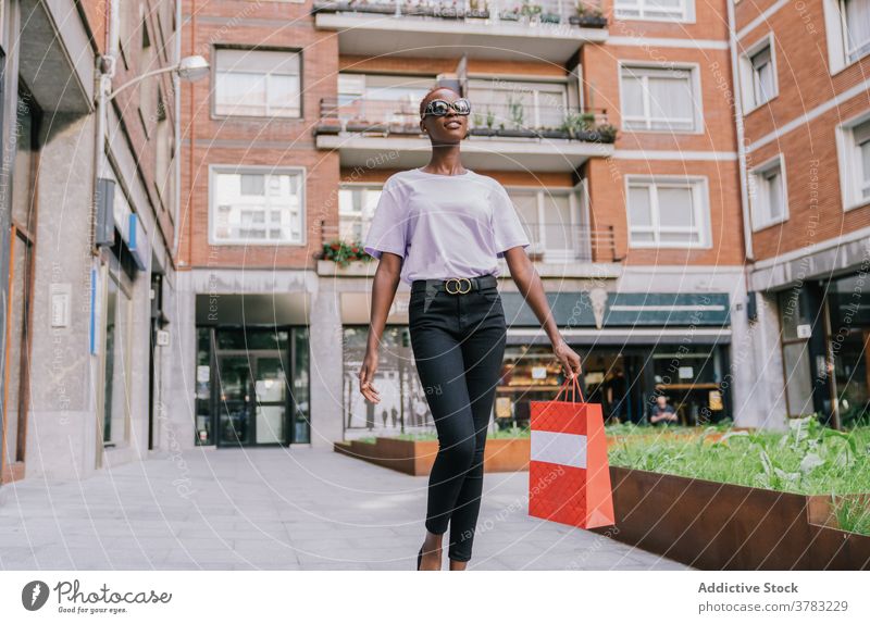 Trendy schwarze Frau mit Einkaufstasche Bummeln auf der Straße Käufer Mode Stoff Stil trendy Kunde urban jung schlank ethnisch Afroamerikaner tausendjährig