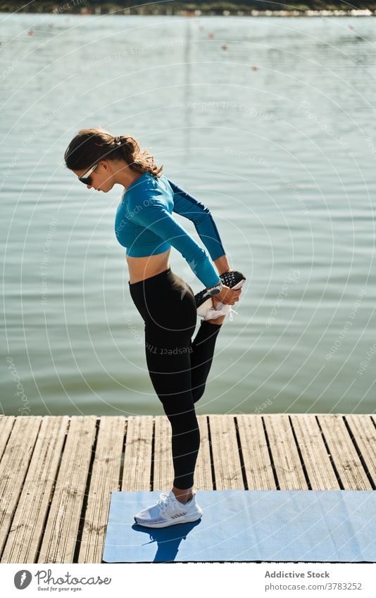 Schlanke Frau in Sportkleidung beim Training am Pier Dehnung Bein passen schlank Fitness Übung Stauanlage sportlich aktiv Aufwärmen Gesundheit beweglich