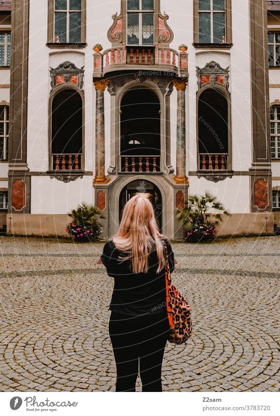 Junge Frau steht vor dem Schloß Füssen Sightseeing füssen bayern sportlich junge frau rückenansicht blond lange haare modisch fashion traditon schloß eingang