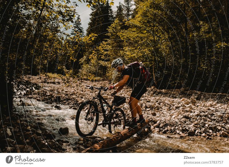 Junge Frau überquert Fluß Bach mit ihrem Mountainbike mountainbike mtb fahrrad abenteuer bach fluss überqueren schieben steine wald alpen berge natur landschaft