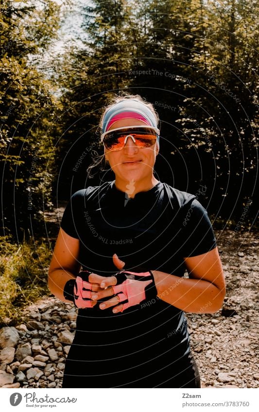 Junge Frau mit Radoutfit radfahren sport sportlich trikot radhandschuhe sonnebrille style modern hübsch schön blond junge frau lachen lächeln glücklich fröhlich