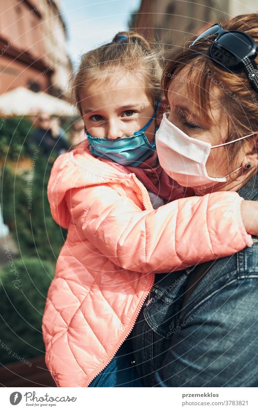 Familienmutter und ihre Tochter stehen auf einer Straße in der Innenstadt und tragen die Gesichtsmasken, um eine Virusinfektion zu vermeiden Anruf Pflege