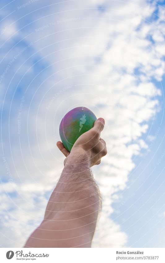 Bunte Mango in einer Männerhand mit dem Himmel als Hintergrund männlich farbenfroh hoch fliegen Hand ökologisch umweltfreundlich tropisch Frucht Südfrüchte