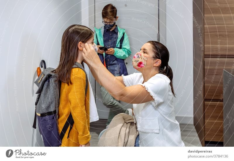 Mutter setzt ihrer Tochter die Maske auf korrekt passende Maske zur Schule gehen zurück zur Schule covid-19 Schutzmaske vorbereitend Coronavirus Pflege