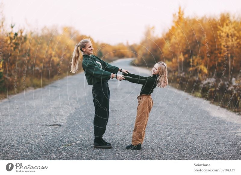 Glückliche reife Mutter und ihre blonde kleine Tochter, die sich beim Spaziergang im Herbst im Park im Freien umarmen und lachen Frau Mama Lächeln lieblich