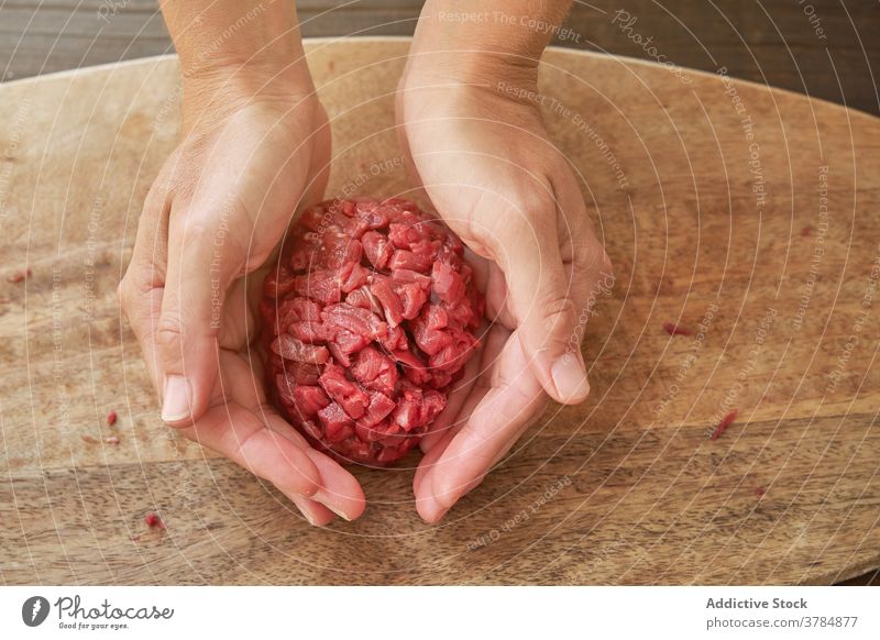 Crop-Köchin bei der Zubereitung von Steak Tartare roh Rindfleisch Koch Frau Küchenchef Fleisch Tradition rund Form Bestandteil Messer Lebensmittel vorbereiten