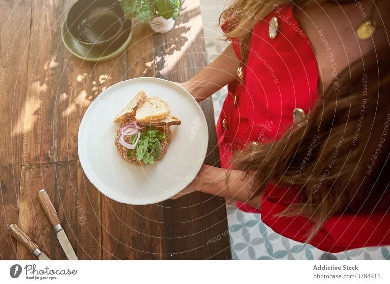 Crop-Frau mit Steak Tartare auf Teller Speise Küche selbstgemacht Hausfrau lecker roh Rindfleisch Fleisch Lebensmittel Tisch hölzern appetitlich frisch Zwiebel