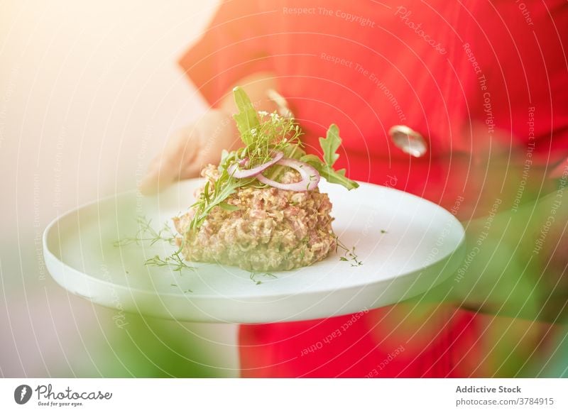 Crop Koch bereitet Steak Tartare in der Küche Rucola Garnierung Speise Küchenchef grün roh Rindfleisch Fleisch frisch geschmackvoll Mittagessen Lebensmittel