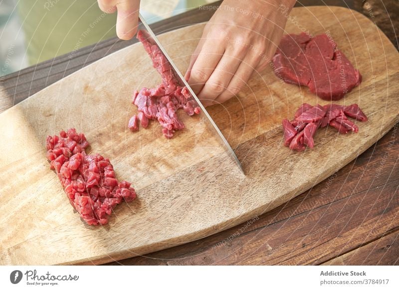 Crop Frau Schneiden von Fleisch in der Küche geschnitten Rindfleisch Koch Steak Tartar Hausfrau vorbereiten Abendessen Speise Schneidebrett frisch hölzern