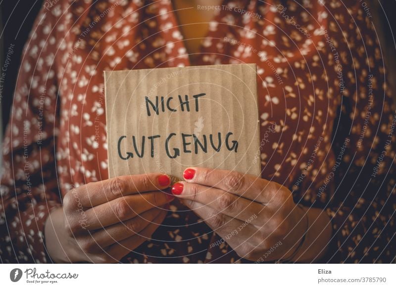 Eine Frau hält ein Schild auf dem "Nicht gut genug" steht. Selbstzweifel. Minderwertigkeitskomplex. kein Selbstbewusstsein minderwertigkeitskomplexe Komplexe