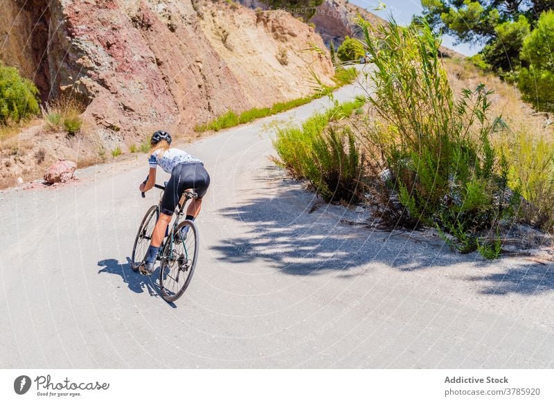 Sportlicher Radfahrer fährt Fahrrad auf Bergstraße Mitfahrgelegenheit Berge u. Gebirge Straße Rückansicht Training anonym aktiv Lifestyle Ausdauer Aktivität