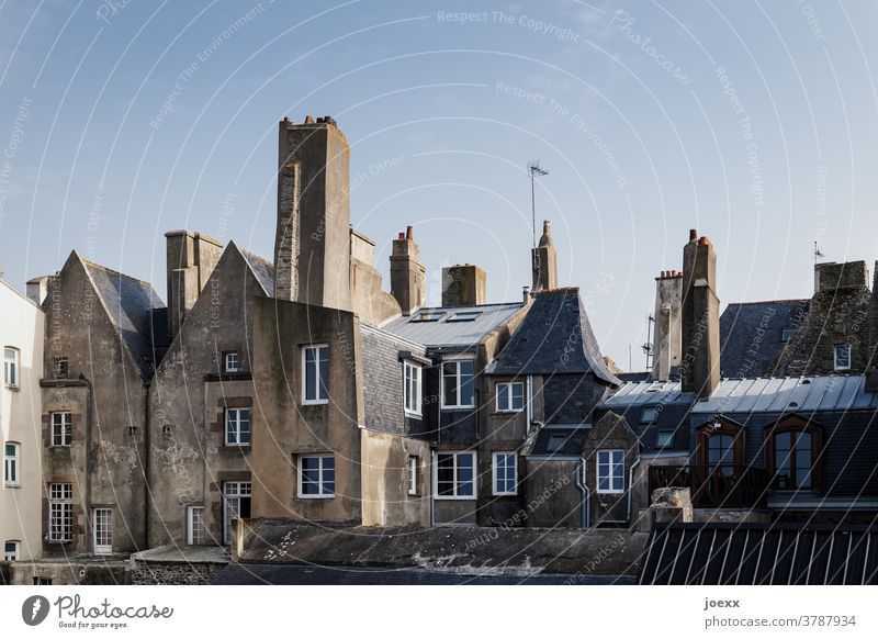 Fassaden historischer Häuser mit Kaminen in einer Altstadt Mauer Fenster Dach Himmel blau Dorf Saint Malo Frankreich Bretagne historischer stadtteil