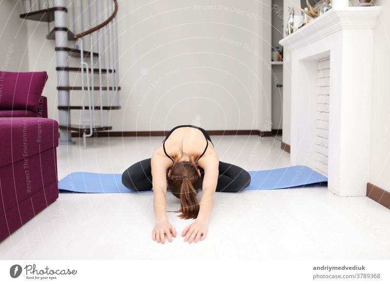 Macht Yoga-Übungen auf der Matte auf dem Boden. Junge Frau mit schlanker Körperform in Sportkleidung hat einen Fitness-Tag zu Hause im Haus. jung