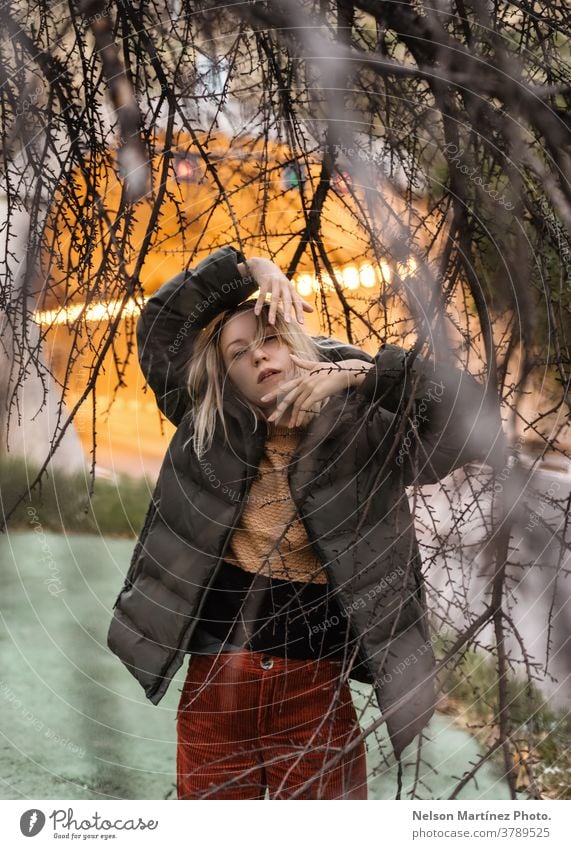 Porträt einer blonden Frau im Herbst, mit einem Tunnel im Hintergrund. Winter warm Stollen Baum Natur Kontrast Regenmantel Farbe filmisch Licht Kaukasier