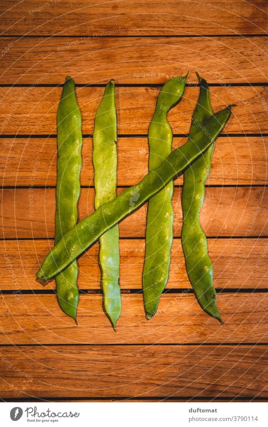 Fünf grüne Bohnen liegen auf Holztisch zählen Stangenbohnen fünf Ernährung Makroaufnahme Strukturen & Formen 5 struktur abstreichen Vegetarische Ernährung