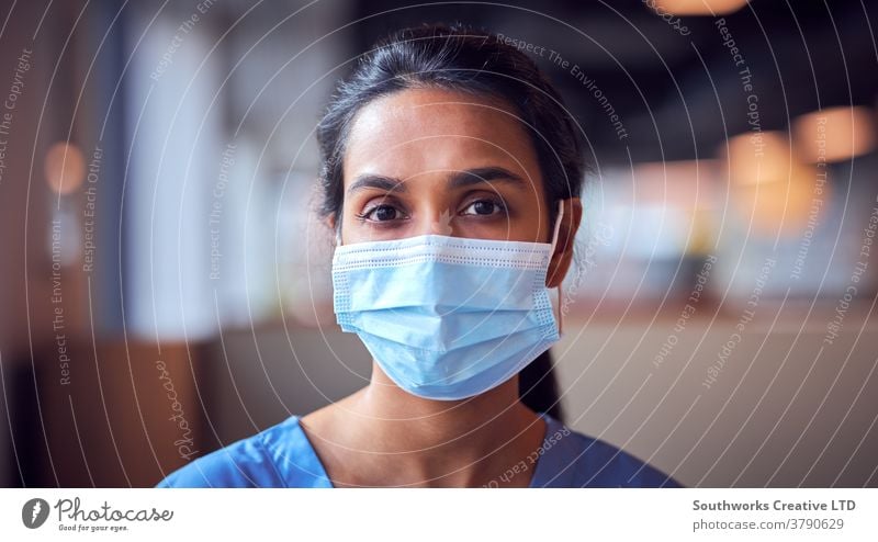 Weibliche Ärztin mit Gesichtsmaske und Kittel unter Druck im geschäftigen Krankenhaus während einer Gesundheitspandemie Arzt Krankenpfleger bürstet