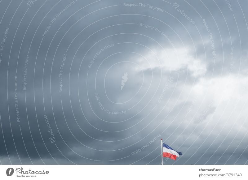 Fahne von Schleswig-Holstein im Wind unter dunklen Wolken Himmel Außenaufnahme wehen Schleswig- Holstein dunkle Wolken trotzen