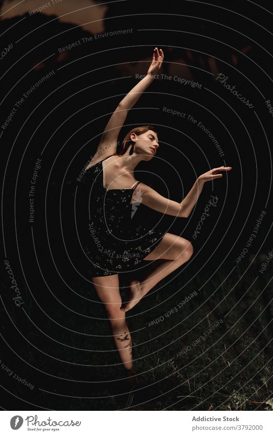 Anmutige Frau tanzt im dunklen Park Balletttänzer Ballerina Tänzer dunkel Wiese Choreographie beweglich Talent Island Kleid Natur elegant Gleichgewicht Künstler