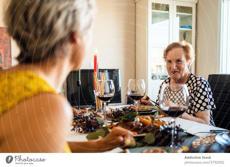 Lächelnde Frauen interagieren am Tisch während des Weihnachtsessens Lebensmittel Abendessen Alkohol Freund feiern Weihnachten festlich flach Rotwein Traube