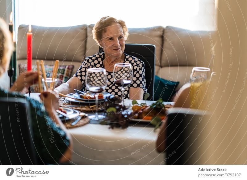 Lächelnde Frauen interagieren am Tisch während des Weihnachtsessens Lebensmittel Abendessen Alkohol Freund feiern Weihnachten festlich flach Rotwein Traube