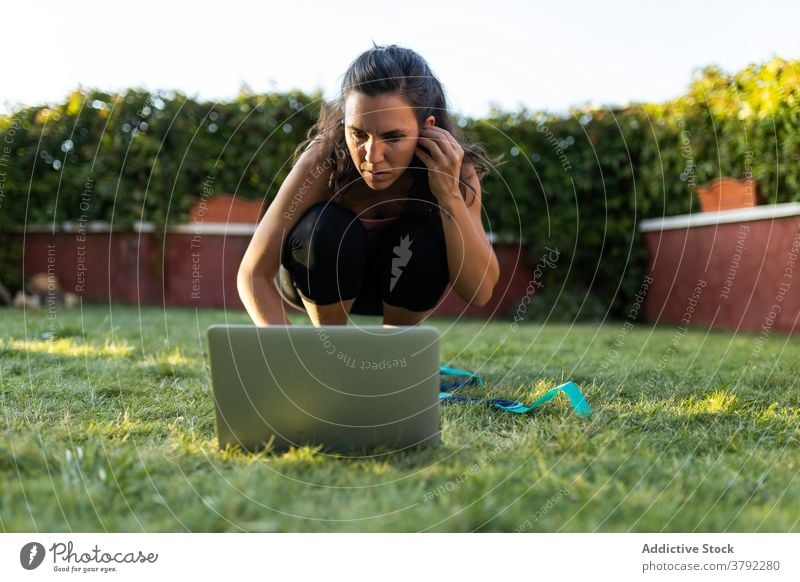 Sportlerin schaut sich während des Trainings ein Online-Tutorial an online Frau wählen pflücken Laptop benutzend Hinterhof Sommer Fitness Browsen Athlet