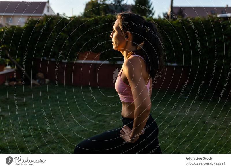 Schlanke Frau macht Übungen im Innenhof im Sommer Ausfallschritt Training Laptop online Tutorial benutzend Athlet Sonnenuntergang Sportbekleidung Gesundheit