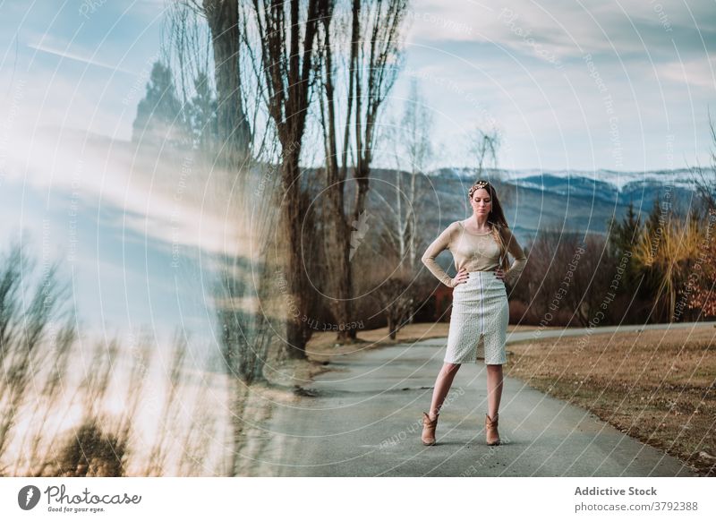 Anmutige Frau stehend mit Armen auf Taille im Frühling Natur selbstbewusst Hand auf der Taille Stil Körperhaltung elegant Bekleidung traumhaft Vorschein cool