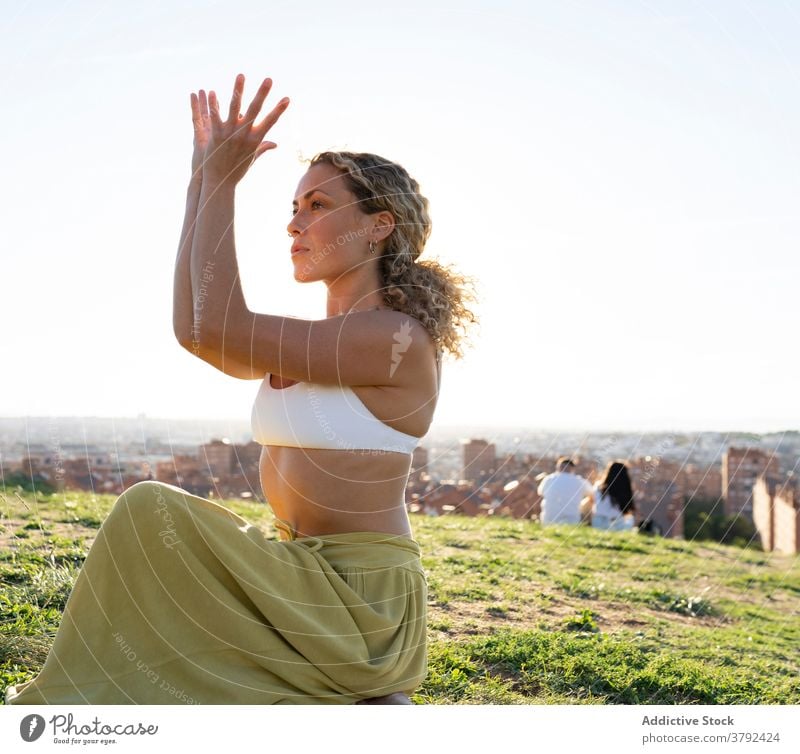 Anmutige Frau sitzt in Cow Face Pose auf einem Hügel Yoga Kuhgesichtshaltung Arm angehoben Vitalität Asana Barfuß Gesunder Lebensstil Fokus sitzen Achtsamkeit