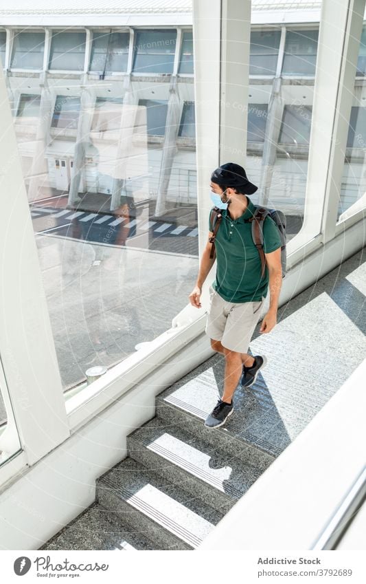 Männlicher Reisender in Maske im Flughafen Mann Mundschutz Coronavirus warten Spaziergang im unteren Stockwerk Abheben Urlaub männlich Projekt verhindern