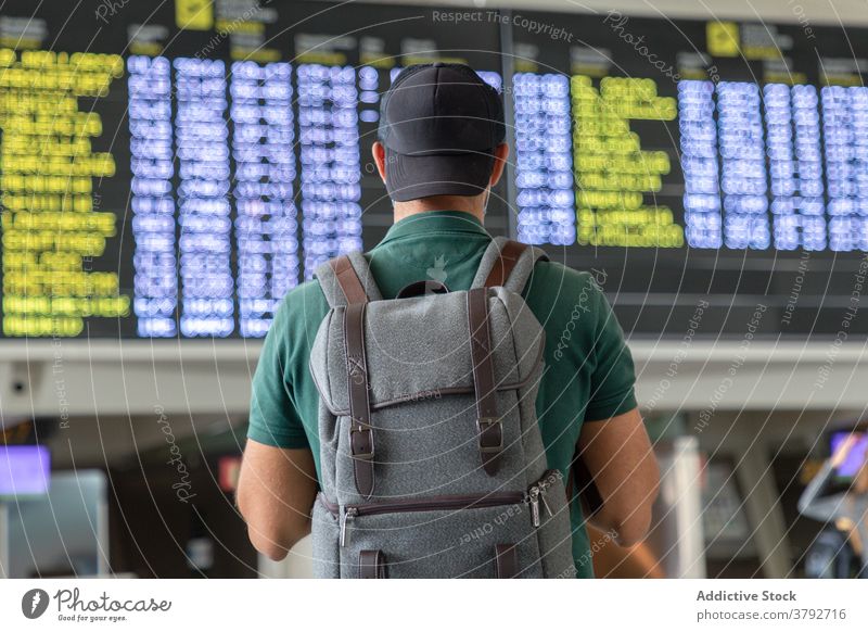 Unbekannter Mann mit Rucksack im Flughafen Abheben Holzplatte Zeitplan Reisender prüfen warten Tourist männlich international Urlaub reisen Ausflug Passagier