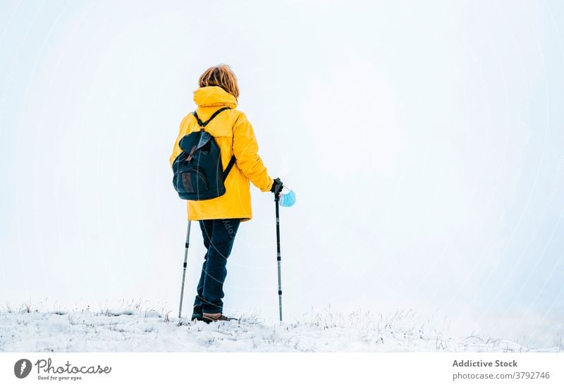 Wanderer mit Schutzmaske auf verschneitem Gelände stehend Trekking Reisender Mundschutz Coronavirus aktiv Schnee Berge u. Gebirge Rucksack Abenteuer COVID19