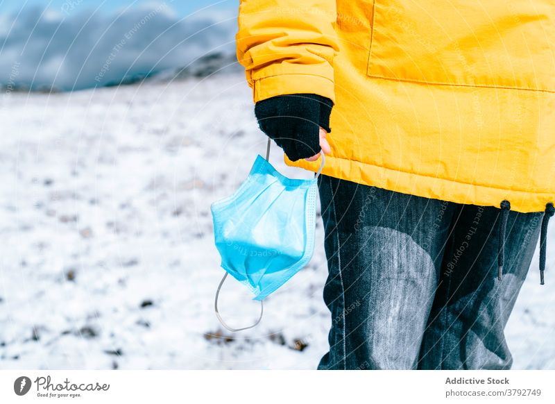 Wanderer mit Schutzmaske auf verschneitem Gelände stehend Trekking Reisender Mundschutz Coronavirus aktiv Schnee Berge u. Gebirge Rucksack Abenteuer COVID19