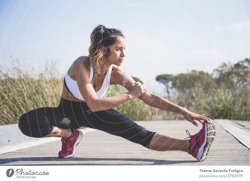 Attraktive Frau macht Dehnungsübungen im Freien Sportkleidung sportlich Mädchen rennen Herz Fitness Joggen Lifestyle Sportbekleidung Park See Sonne springend