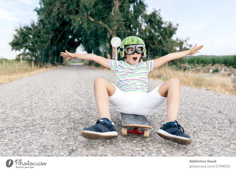 Glücklicher Junge auf Skateboard in Schutzbrille Schutzhelm Spaß haben sorgenfrei Kindheit aufgeregt Inhalt Straße stylisch Bekleidung Brille dekorativ Sommer