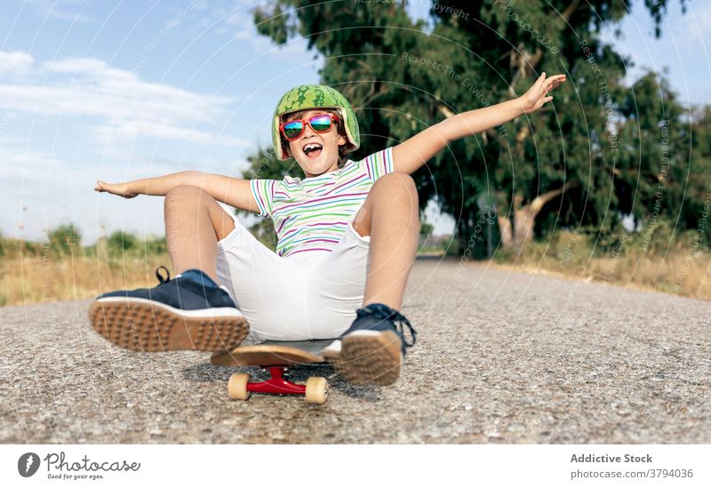 Glücklicher Junge auf Skateboard in Schutzbrille Schutzhelm Spaß haben sorgenfrei Kindheit aufgeregt Inhalt Straße stylisch Bekleidung Brille dekorativ Sommer