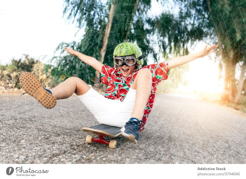 Glücklicher Junge auf Skateboard in Schutzbrille Schutzhelm Spaß haben sorgenfrei Kindheit aufgeregt Inhalt Straße stylisch Bekleidung Brille dekorativ Sommer