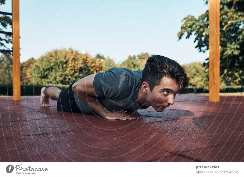 Junger Mann macht Liegestütze auf rotem Gummiboden während seines Trainings in einem modernen Trainingspark für Gymnastik calisthenics Pflege Kaukasier