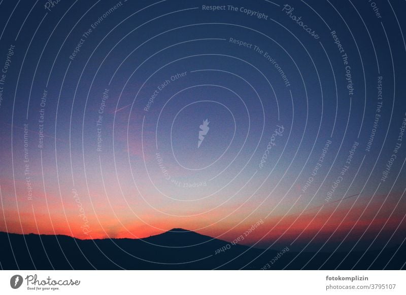 dunkle Silhouette einer Hügelkuppe vor rotblauem Abendhimmel Abendlicht Sonnenuntergangsstimmung Sonnenuntergangslandschaft Hügellandschaft Abenddämmerung